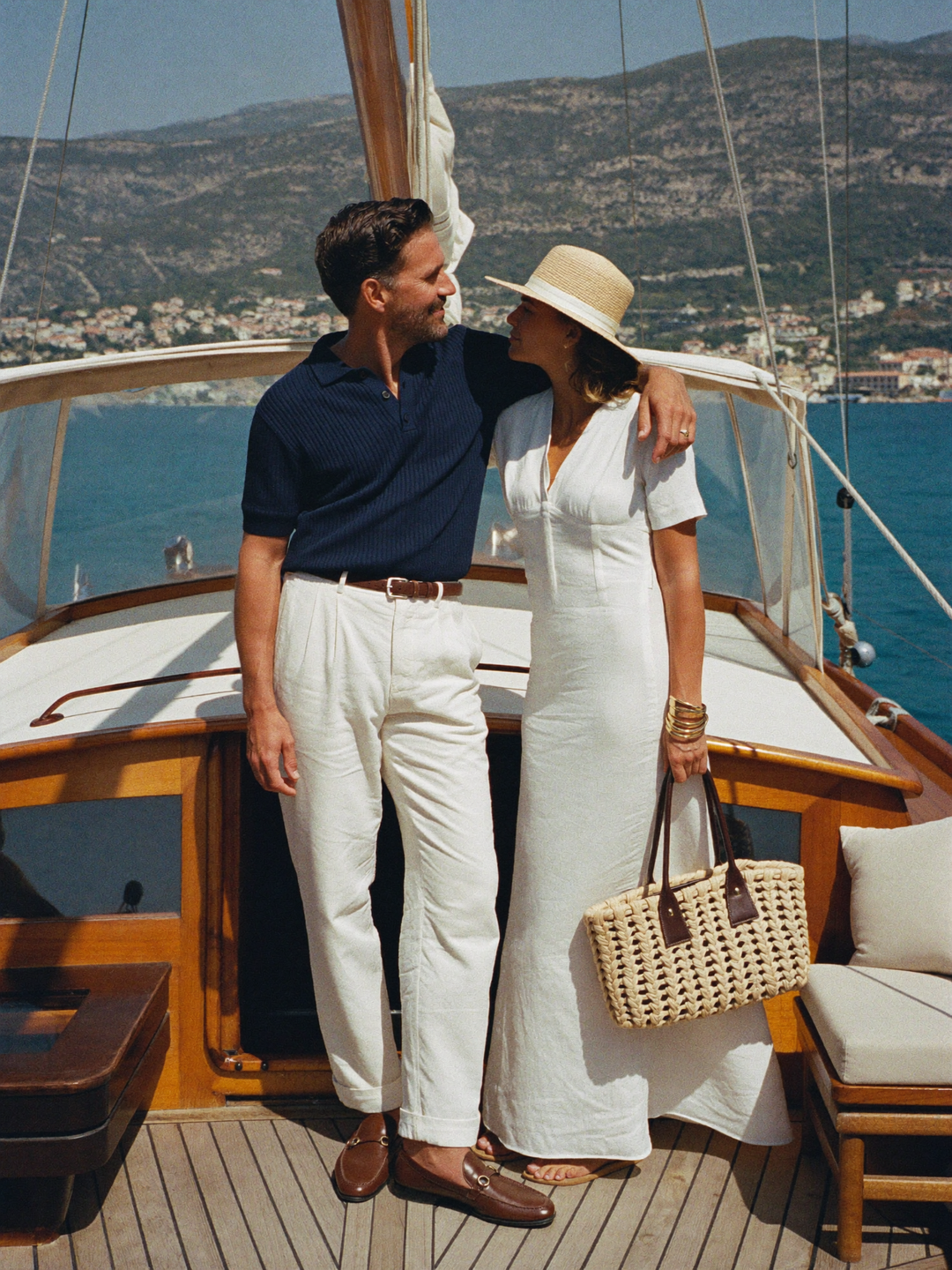 Couple in summer linens on the deck of a classic sailing yacht